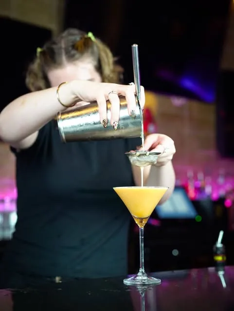 A bartender pouring a passion-fruit martini